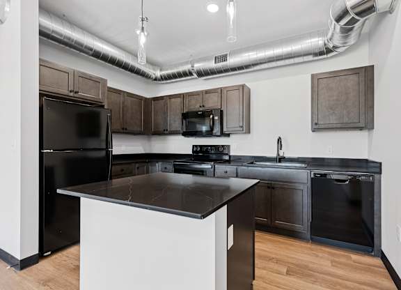 A modern kitchen with a black refrigerator and stove.