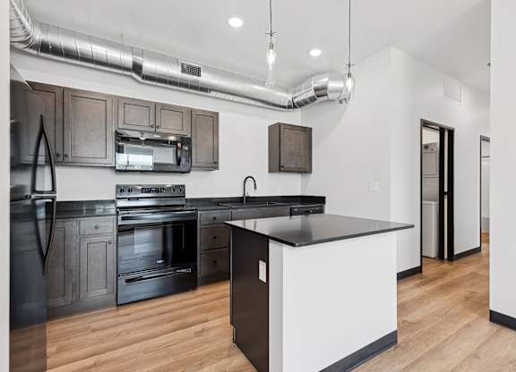 A modern kitchen with a black countertop and stainless steel appliances.