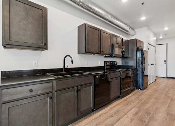 A kitchen with dark wood cabinets and a black countertop.