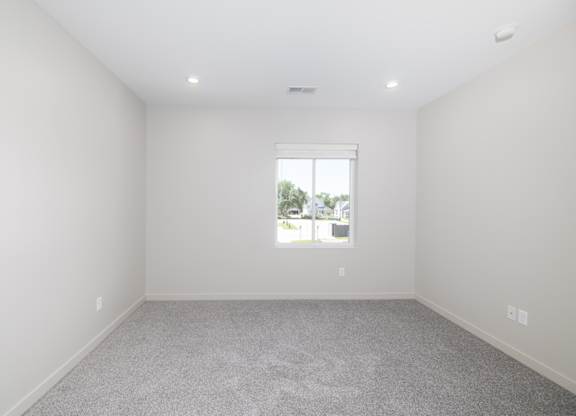 A room with a window and carpeted floor.