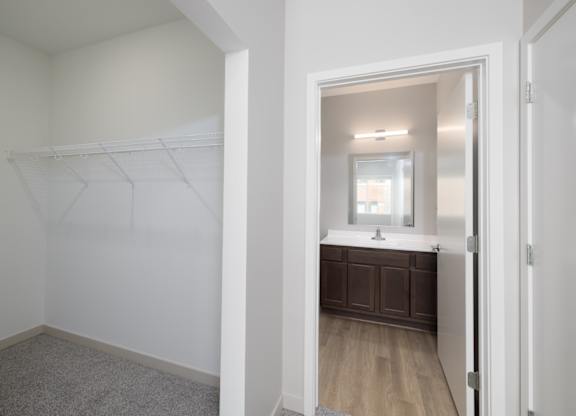A white bathroom with a wooden vanity and a mirror.