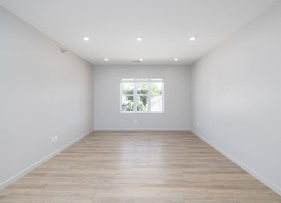 A room with wooden flooring and white walls.