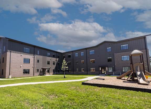 A playground area is located in front of a modern building.