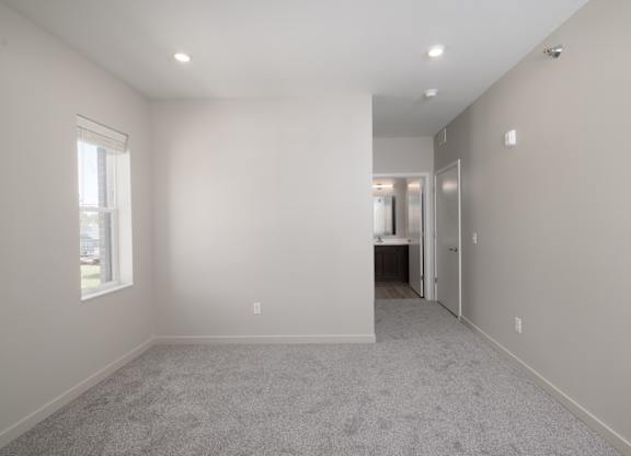 A spacious room with a carpeted floor and a window.