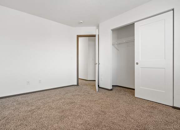 A carpeted room with a white door and a white wall.