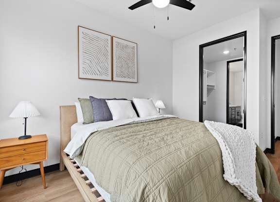 A bedroom with a bed, a nightstand, a lamp, and a ceiling fan.