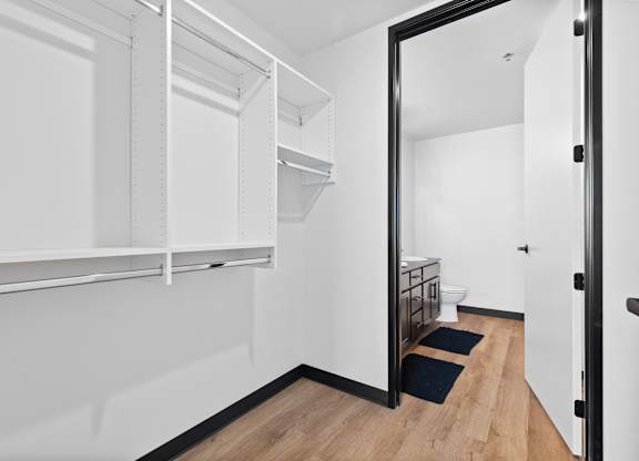 A white hallway with a black door and a black mat on the floor.