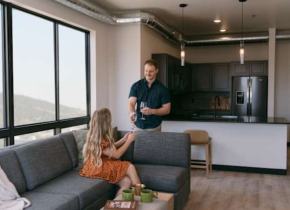 A man and a girl are sitting on a grey sofa in a modern kitchen.