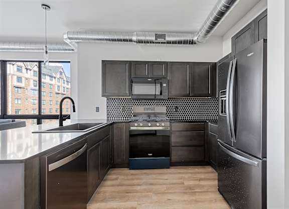 A modern kitchen with a stainless steel refrigerator and black cabinets.