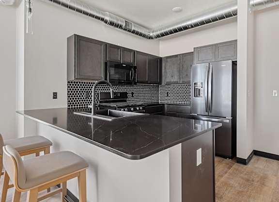 A kitchen with a black counter top and a refrigerator.