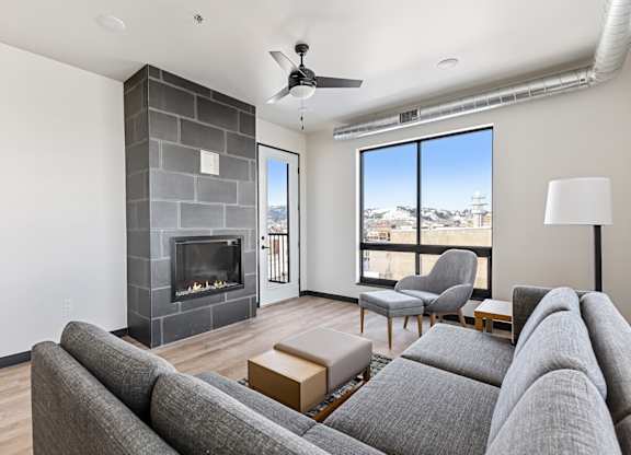A living room with a grey couch and a fireplace.