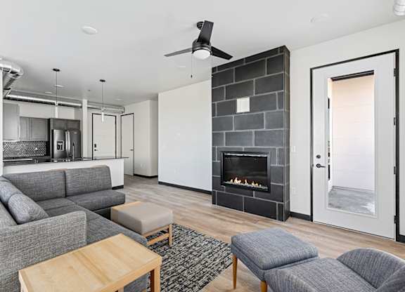 A modern living room with a grey couch, a wooden coffee table, and a fireplace.