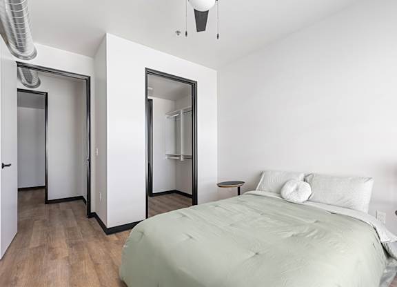 A bedroom with a bed, nightstand, and mirrors.
