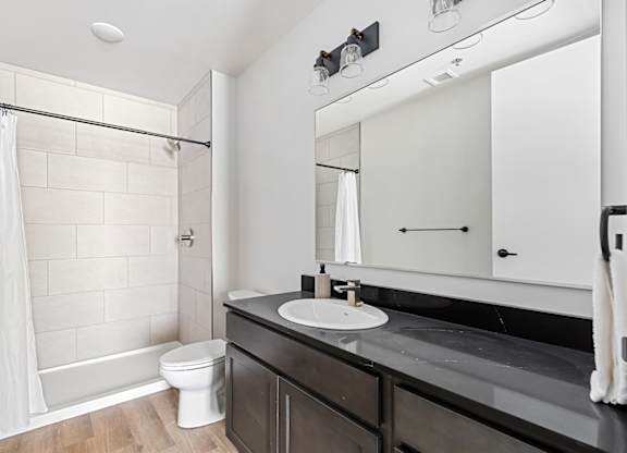 A bathroom with a white toilet, a sink, and a shower.
