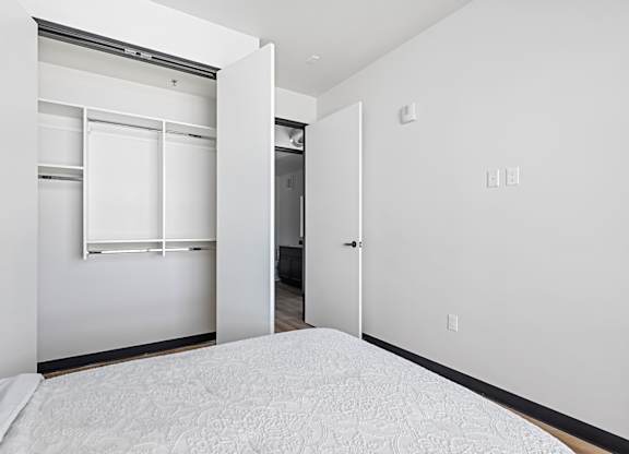 A white bedroom with a bed and a closet.