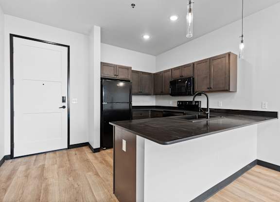A kitchen with a black countertop and white walls.