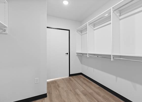 A white room with a door and a shelf.