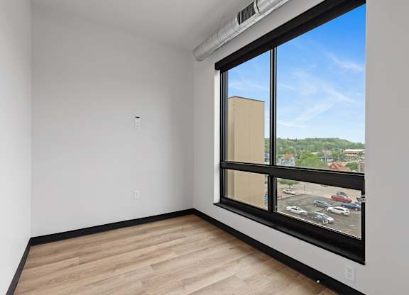A room with a large window overlooking a parking lot.