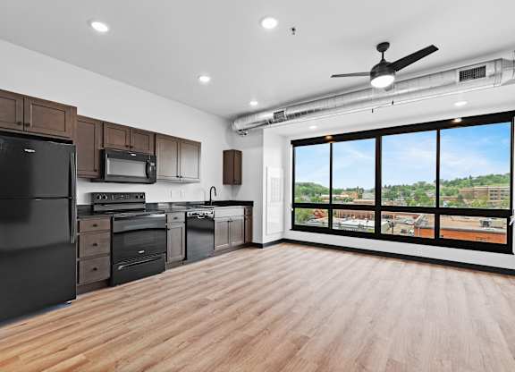 A spacious kitchen with wooden floors and a large window overlooking the city.