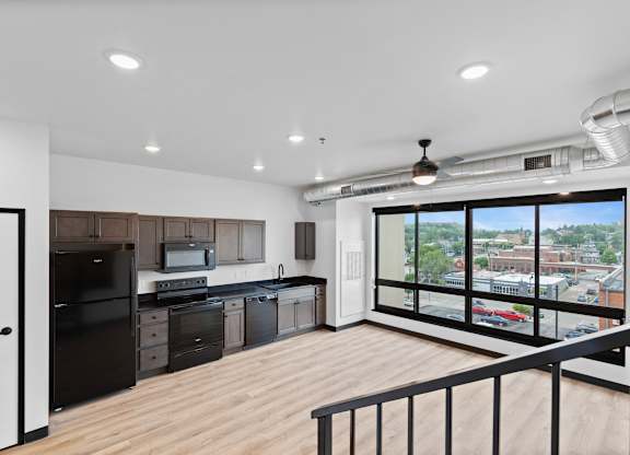 A modern kitchen with black appliances and wooden floors.