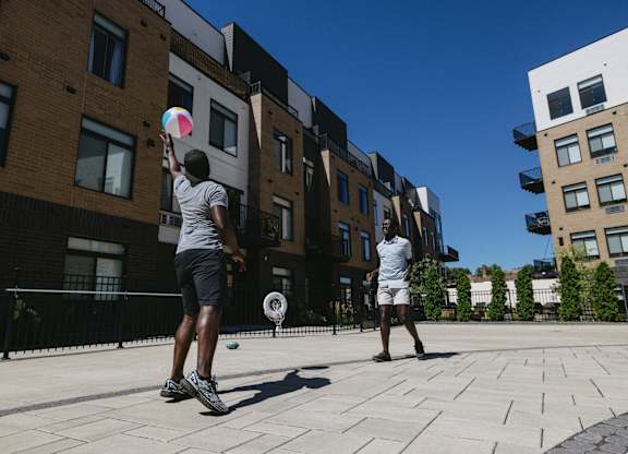 Two men playing with a kite in a courtyard.