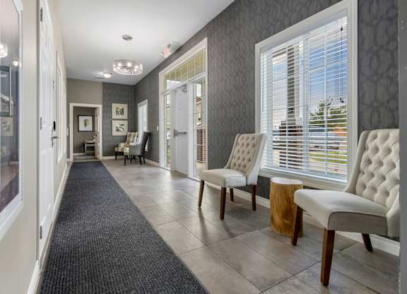 A hallway with a black carpet and white chairs.