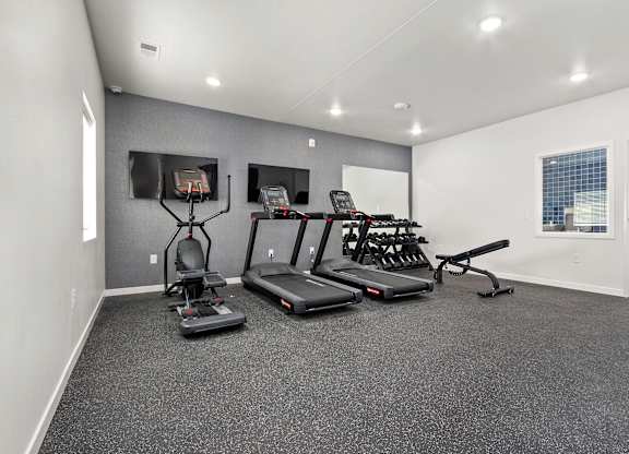 A spacious gym with treadmills, elliptical machines, and a weight bench.