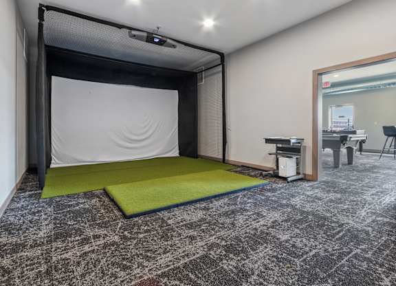 A room with a black and white patterned carpet and a green mat in front of a black screen.