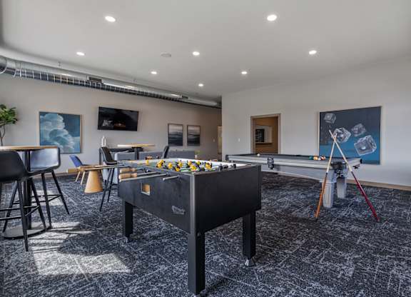 A room with a pool table and a foosball table.