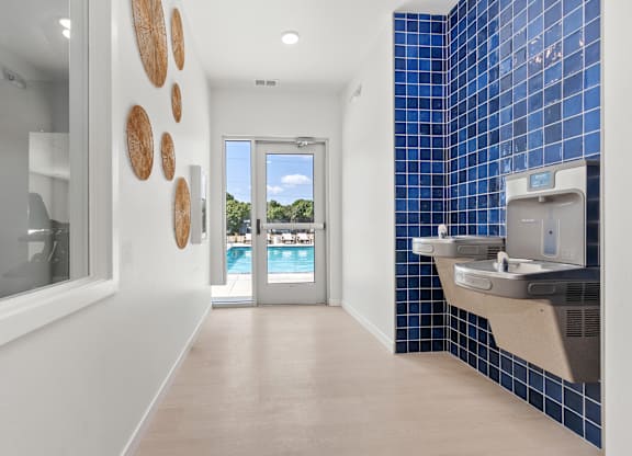 A bathroom with a blue tiled wall and a white sink.
