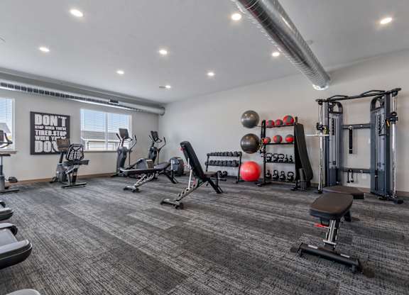 A gym with a variety of equipment including a bench, weights, and a squat rack.