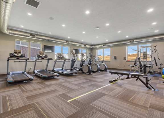 A gym with treadmills, elliptical machines, and weights.