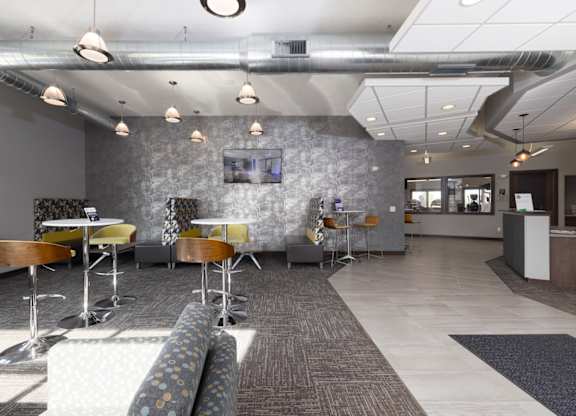 A modern office space with a grey stone wall and a long carpeted table.