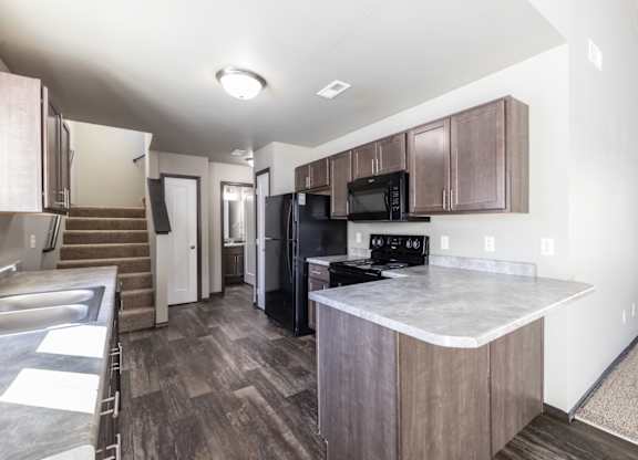 A kitchen with a black fridge and microwave.