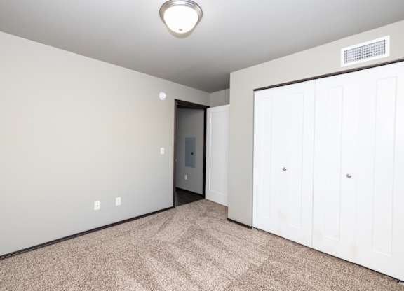 A room with a carpeted floor and a white door.