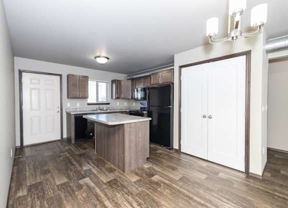 A kitchen with a white door and a wooden floor.
