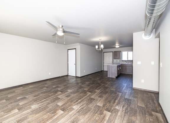 A room with a ceiling fan and wooden flooring.
