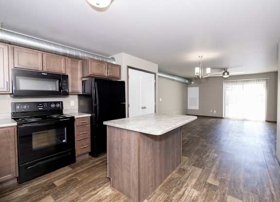 A kitchen with black appliances and wooden floors.