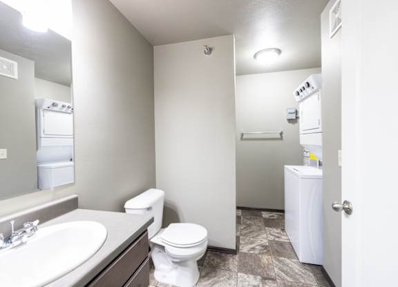 A bathroom with a toilet, sink, and a white cabinet.