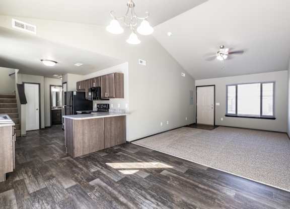 A spacious living room with a kitchen area in the background.