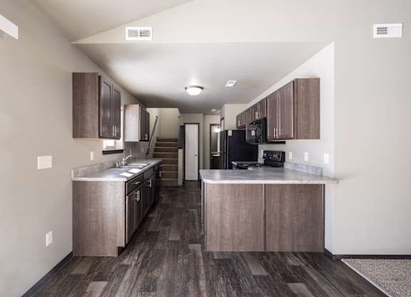 A kitchen with wooden floors and a black refrigerator.