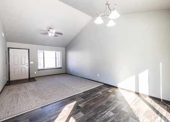 A spacious room with a ceiling fan and a door.