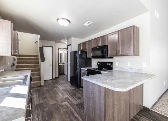 A kitchen with a black fridge and microwave.