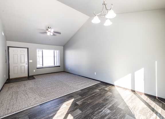 A spacious room with a ceiling fan and a door.