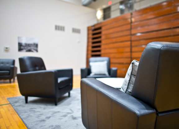 A black leather couch sits in a room with other black leather furniture.