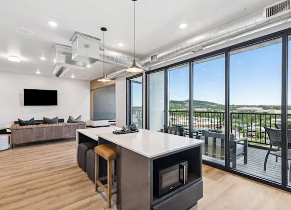 A modern kitchen with a large island and a view of the outdoors.