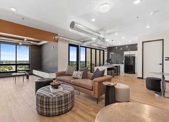 A modern living room with a brown couch and a checkered ottoman.