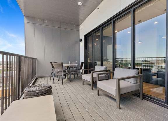 A balcony with a table and chairs overlooking a cityscape.