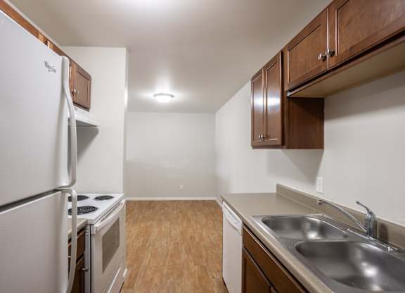 a kitchen with stainless steel appliances and wooden cabinets and a white stove and refrigerator