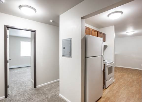 a room with a refrigerator and a stove and a door to a kitchen